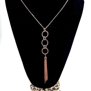 Elegant rose gold-tone tassel necklace with triple ring pendant.
